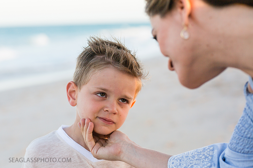 Mother giving love and advice to her young son on the beach during maternity photos in Vero Beach Florida
