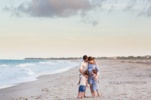 Expecting family hugging on the beach during maternity photos in Vero Beach Florida