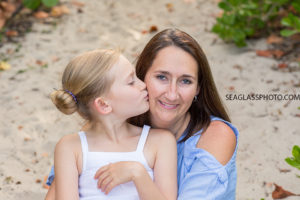 Daughter kissing mom on the cheek during family photo shoot on the beach in Vero Beach Florida