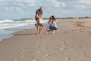 Daughters hugging their parents on the beach during family photo shoot in Vero Beach Florida