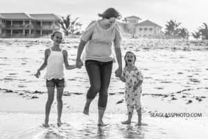 A black and white photo of a mom and her daughters in the water on the beach in Vero Beach Florida
