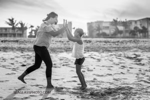 A black and white photo of a mom and her oldest daughter playing on the beach during family photo shoot in Vero Beach Florida
