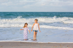 Two sisters playing in the water on the beach during family photo shoot in Vero Beach Florida
