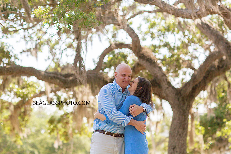 Mother and father hugging beneath the trees at Riverside Park in Vero Beach Florida