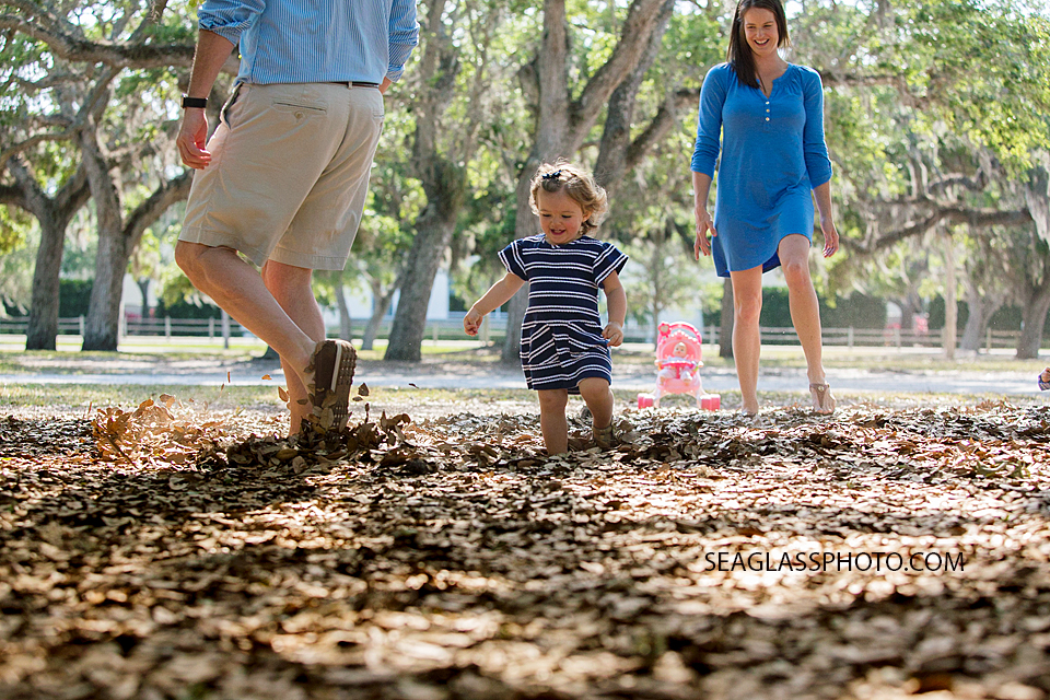 Parents watch as their daughter plays in the leaves at Riverside Park in Vero Beach Florida