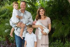 Family poses infront of palm trees during there daughters newborn session in Vero Beach Florida