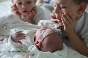Close up of older brothers making faces at their little sister during newborn shoot in Vero Beach Florida