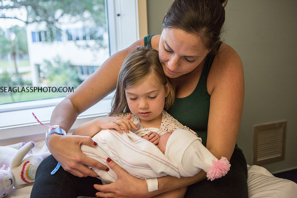 Big sister holds her new little sister for the first time with Mom supporting her in vero Beach Florida
