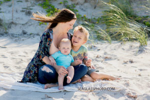 Mom sits with her two sons on the beach in front of the dunes during family photos in Vero Beach Florida