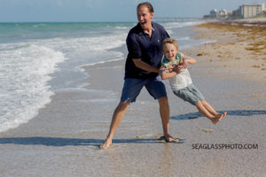 Father pretends to through his oldest son into the water during family photos in Vero beach Florida