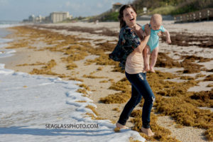 Mom tries to get away from the water while holding her youngest son during family photos in Vero Beach Florida