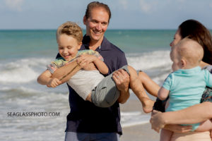 Close up of Mom and Dad holding their sons on the beach during family photos in Vero beach Florida