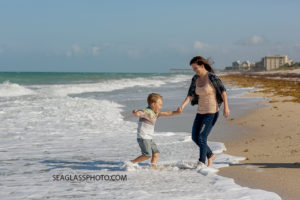 Mom plays with her oldest son i the water on the beach in Vero Beach Florida