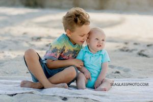 Big brother hugs his little brother on the beach during family photos in Vero Beach Florida