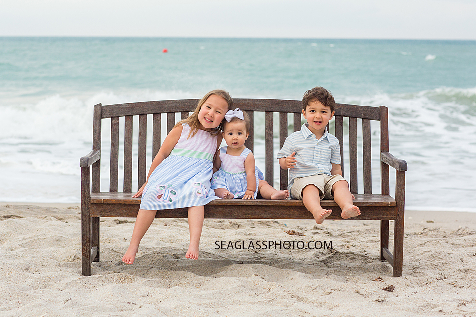Siblings pose on a bench at johns island beach club during family photos in Vero Beach Florida
