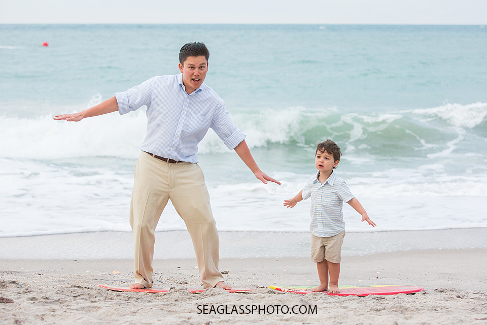 Father and son pretend to surf on the sand at johns island beach club during family photos in Vero Beach Florida