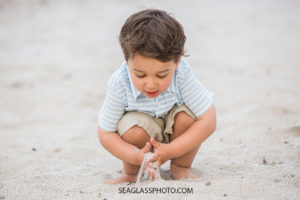 Little boy plays with sand on the beach at johns island beach club during family photos in Vero Beach Florida