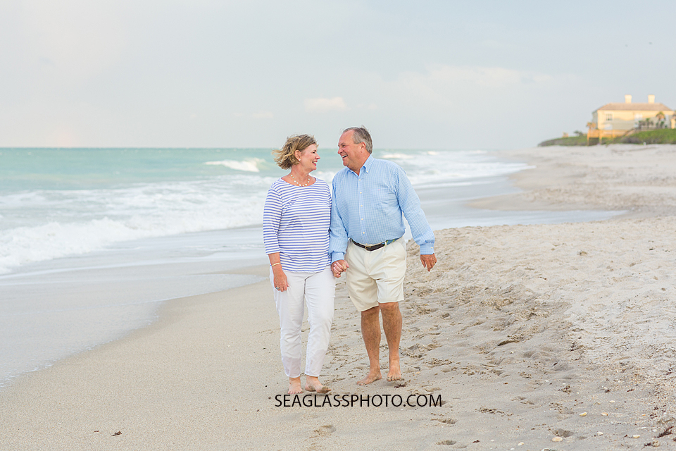 Husband and wife walk and talk on the beach at johns island beach club during family photos in Vero Beach Florida