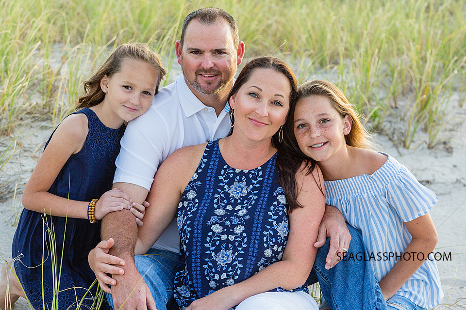 Family sitting on the beach in front of the dunes during family photo shoot in Vero Beach Florida