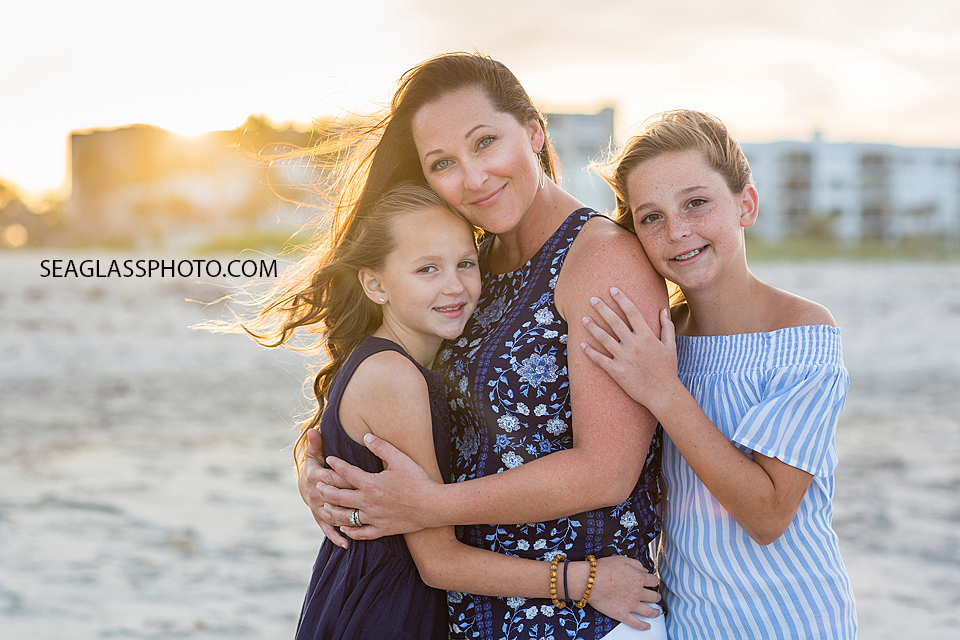 Mom and daughters hugging on the beach during sunset in Vero Beach Florida