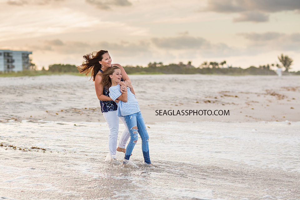 Mom and oldest daughter playing in the water at the beach during family photos in Vero Beach Florida