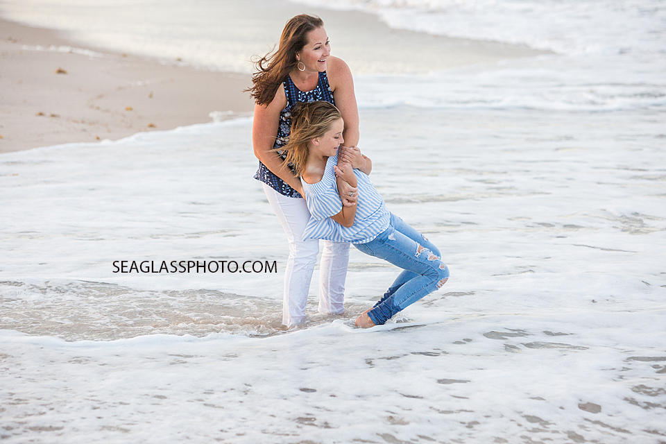 Oldest daughter playing with her mom in the water at the beach during family photo shoot in Vero Beach Florida