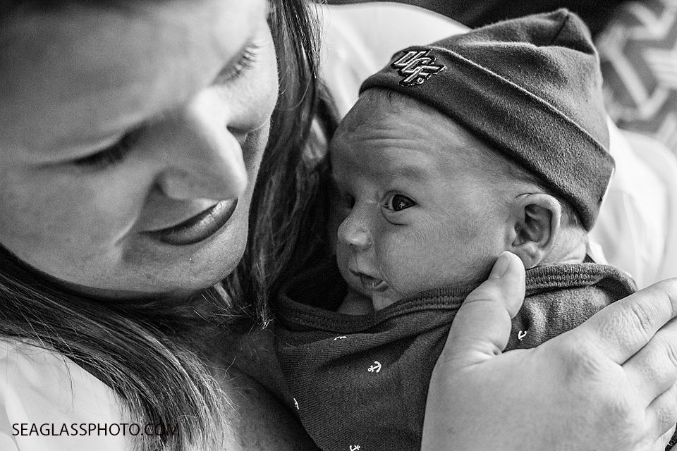 Mom holds her newborn son as he wears their family's favorite football team on his beanie during newborn shoot in Vero Beach Florida
