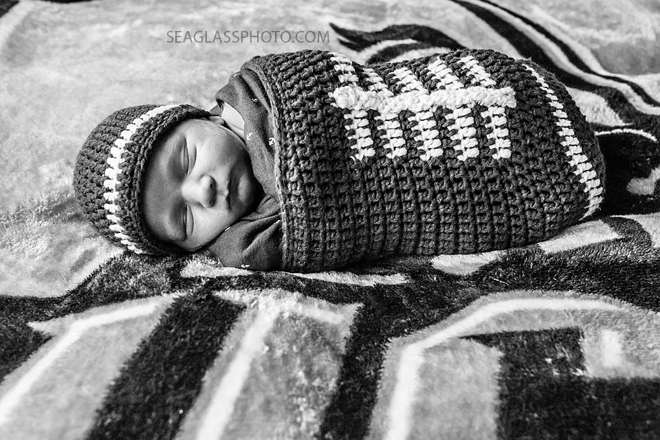 Black and white photo of newborn baby boy sleeping dressed in a football outfit during newborn session in Vero Beach Florida