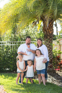 Vertical photo of family posing for the camera during newborn session in Vero Beach Florida