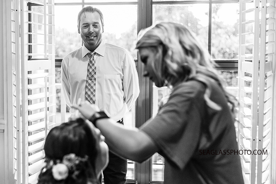 Black and white photo of bride getting makeup done as her father watches during wedding photo shoot in Vero Beach Florida