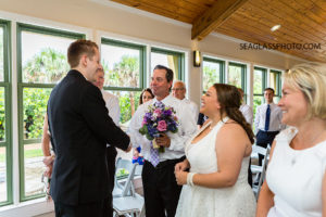 Father of the bride shakes the grooms hand as he passes on his daughter during the wedding in Vero Beach Florida
