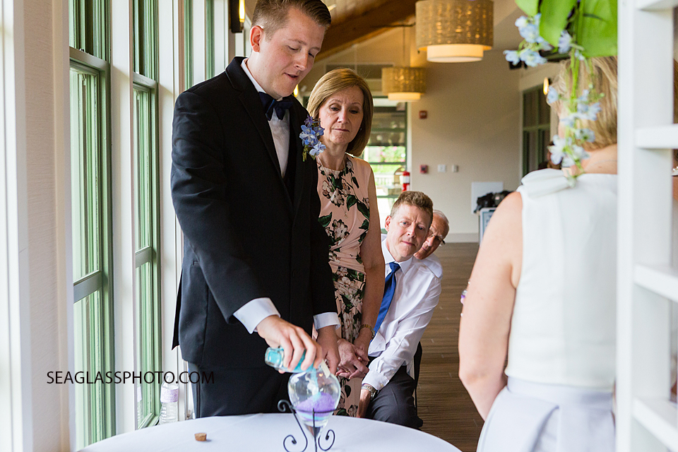 Groom adds the sand to the glass to symbolize the joining of the bride and groom during their wedding in Vero Beach Florida