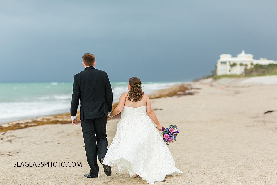 Husband and wife walk together on the beach during their wedding photo shoot in Vero Beach Florida