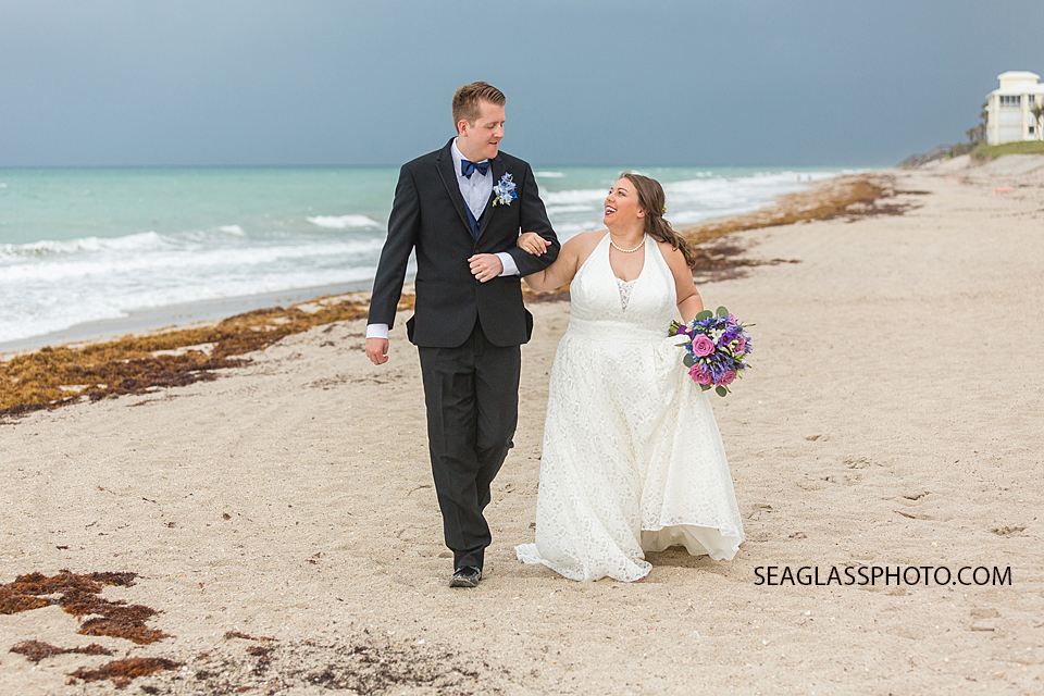 Husband and wife enjoying their walk on the beach during their wedding photo shoot in Vero Beach Florida
