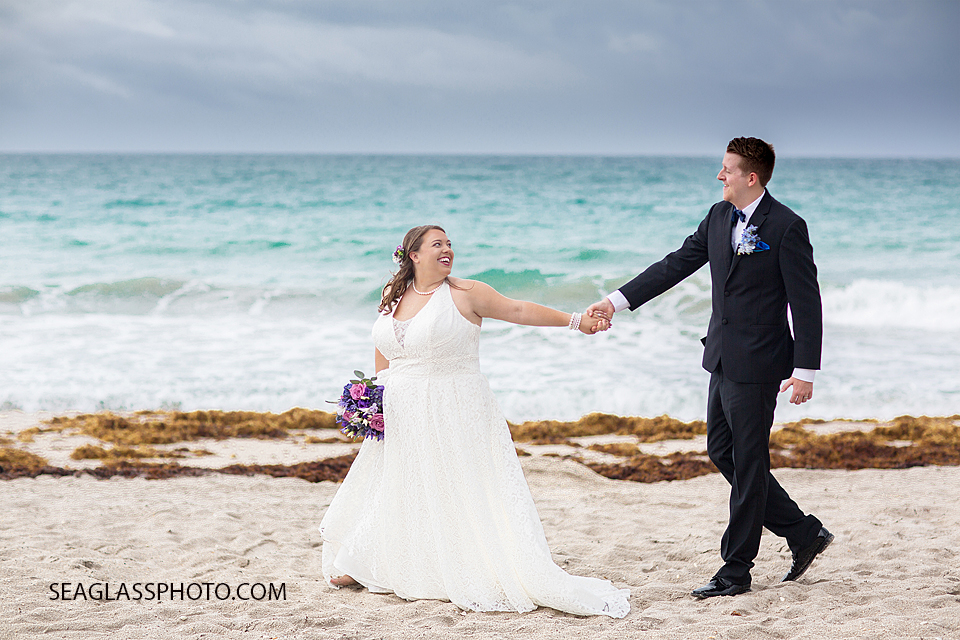 Bride guides her husband on the beach during their wedding photo shoot in Vero Beach Florida