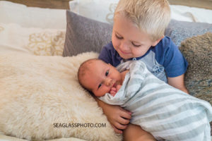 Big brother is very happy to hold his little brother during new born session in Vero Beach Florida