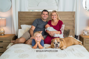 Family poses with their dog to celebrate the birth of their new baby boy during new born session in Vero Beach Florida