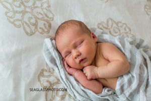 Close up of new born baby boy sleeping and cupping his face during new born session in Vero Beach Florida