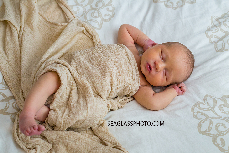 New born baby boy stretching while sleeping during new born session in Vero Beach Florida