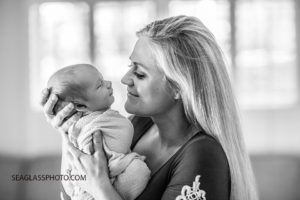 Close up black and white photo of mom holding her new born son as he grins in his sleep at her during new born session in Vero Beach Florida