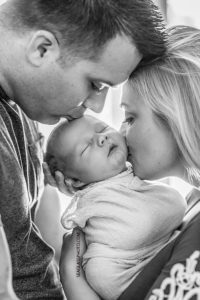 Close up black and white photo of mom and dad kissing their newborn son during new born session in Vero Beach Florida