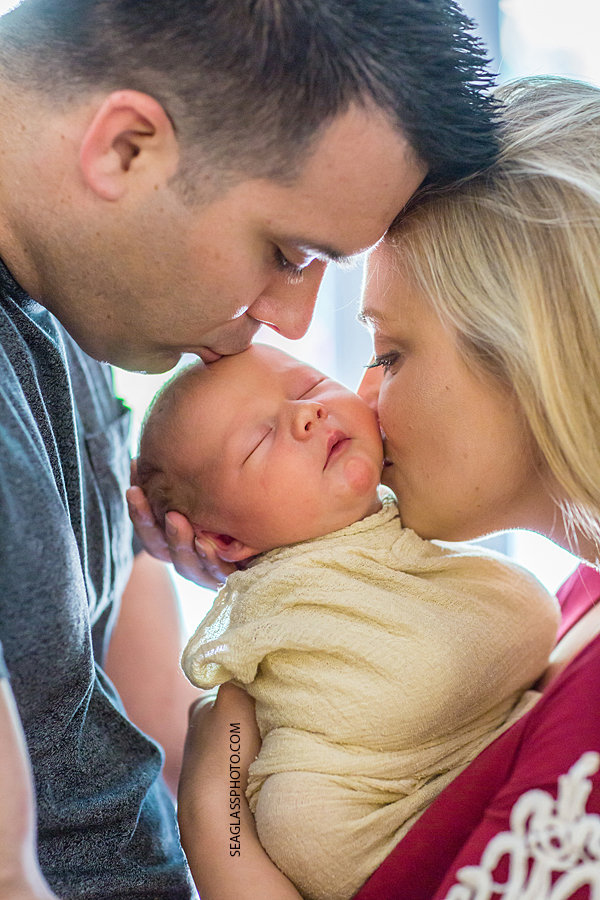 Close up of mom and dad kissing their new born son during new born session in Vero Beach Florida