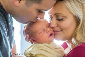 Close up of mom holding her newborn son as dad kisses him on the fore head during new born session in Vero Beach Florida