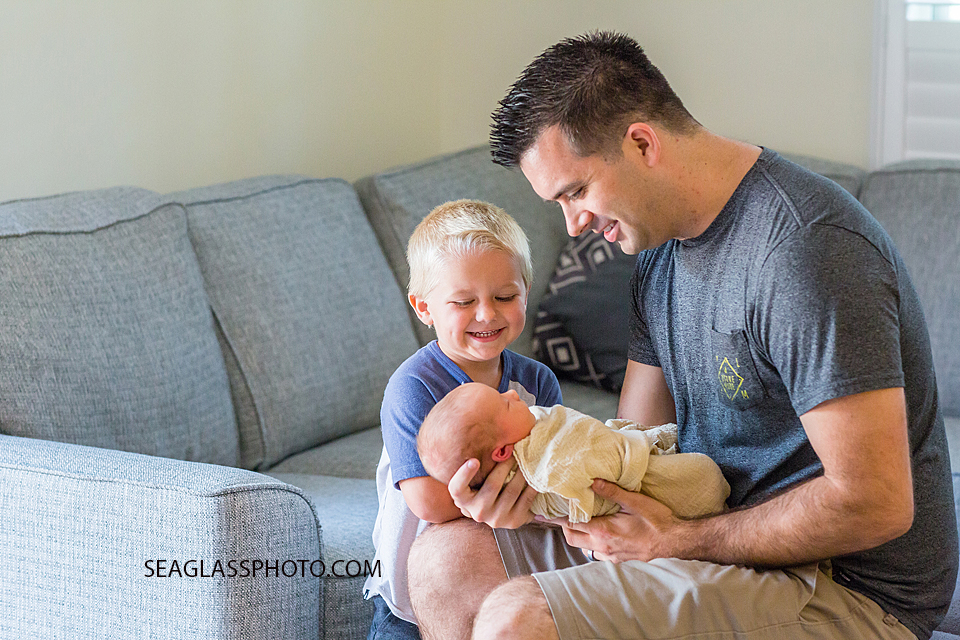 Dad and big brother smile at new born baby boy during new born session in Vero Beach Florida