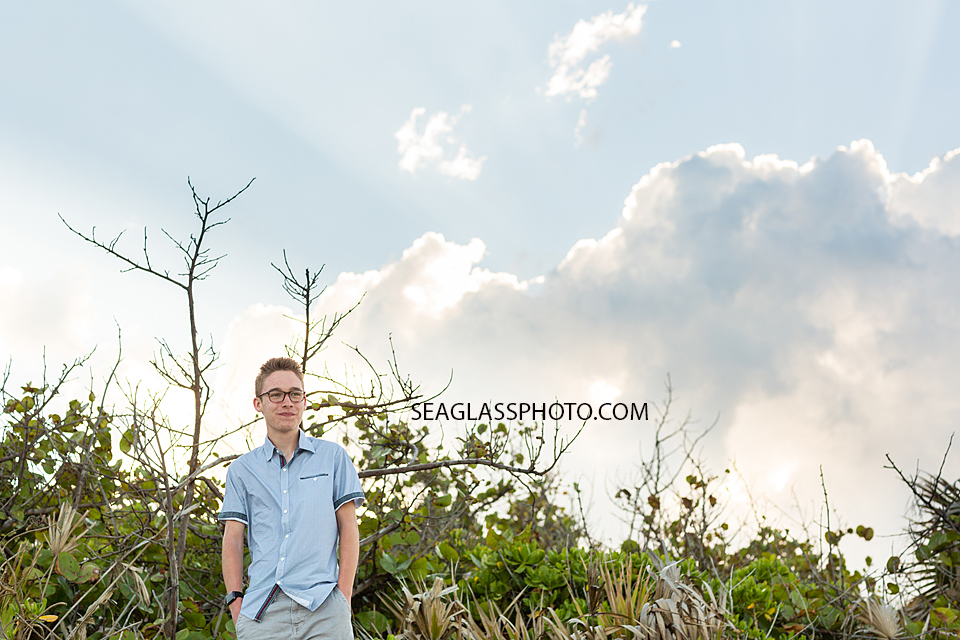 Oldest son poses in front of the dunes at the beach during family photo shoot in Vero Beach Florida
