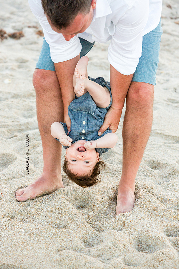 Father plays with his youngest son on the beach during family photo shoot in Vero Beach Florida