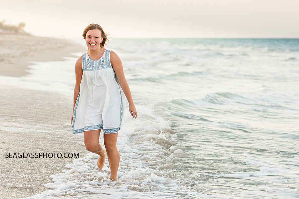 Oldest daughter smiles as she walks on the beach during family photo shoot in Vero Beach Florida