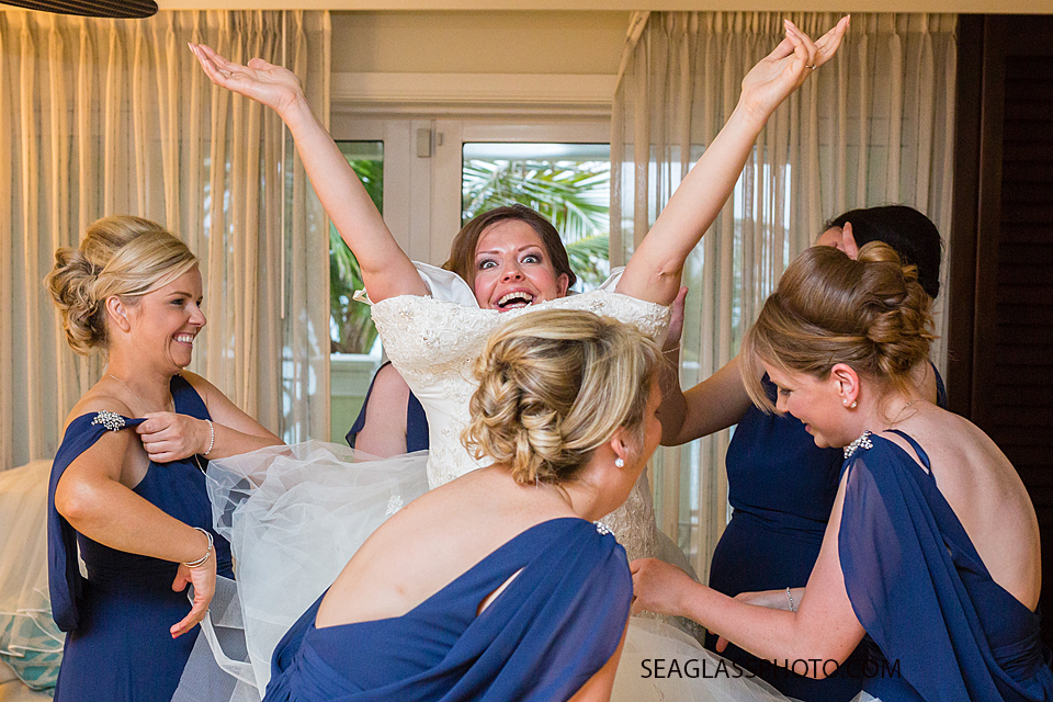 Bride is looking happy to be getting ready for her big day as her bridesmaids help her put her dress on in Vero Beach Florida