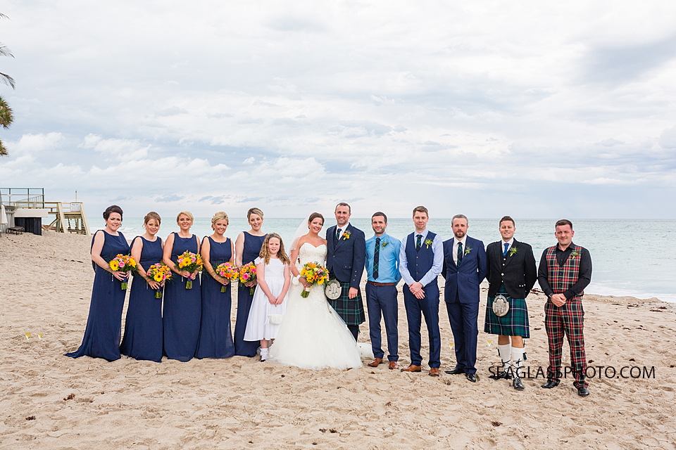All the bridesmaids, Groomsmen and flower girl gather around the newly wed couple on the beach in Vero Beach florida