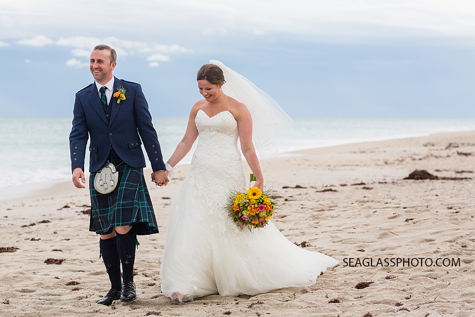 The happy newly wed couple walks on the beach together in Vero Beach Florida